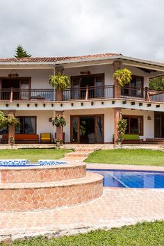 a large house with a pool in front of it and landscaping around the back yard