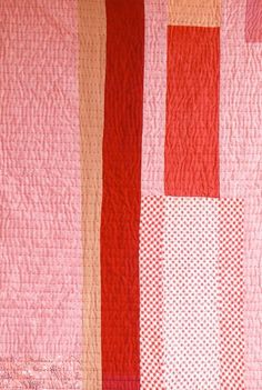 a pink and red quilt with squares on it's sides, in the middle