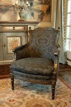 an ornate chair sits in front of a painting