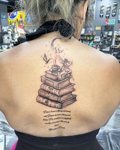 the back of a woman's neck with a stack of books tattoo on it