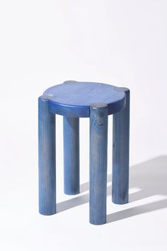 a small blue stool sitting on top of a white floor next to a wooden table