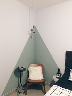 a chair and table in a small room with a wall painted green, white and black