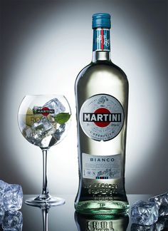 a bottle of martini next to a glass filled with ice