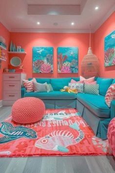 a living room with coral colored walls and blue couches, pink rugs and paintings on the wall