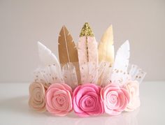 a headband with flowers and feathers on top of a table next to a white wall