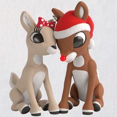 two toy deers sitting next to each other wearing santa's hats on their heads