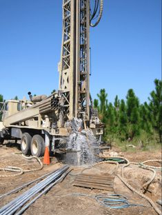 there is a drilling rig that has water coming out of it and hoses connected to the pump