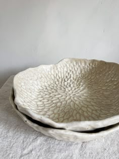 two white bowls sitting on top of a table next to each other with one bowl in the middle