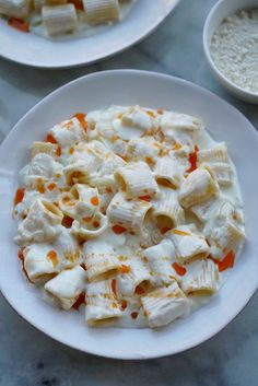 two white plates filled with pasta and cheese