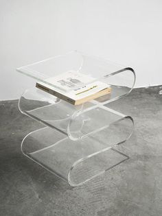 a glass table with a book on it and a white wall in the back ground