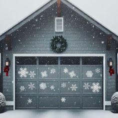 a garage covered in snow with christmas decorations on the front door and wreath above it