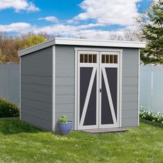 a gray shed sitting on top of a lush green field