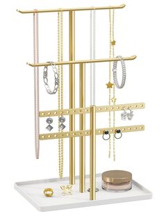 a gold jewelry rack with several necklaces and rings on it, sitting on top of a white tray