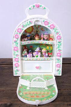 a small doll house with lots of little toys in it's display case on top of a wooden table