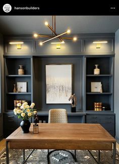 an office with built in bookshelves, desk and flowers on the carpeted floor