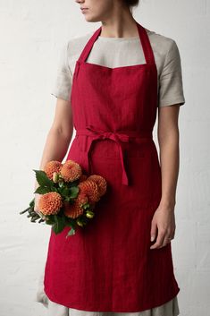 a woman wearing an apron holding flowers in her hand