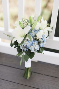 a bouquet of flowers sitting on top of a wooden table next to a white fence