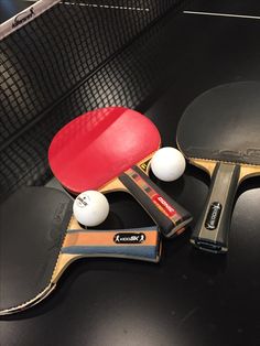 two ping pong paddles and three balls on a table