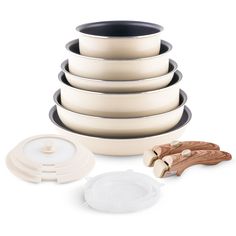 a stack of white and black bowls with lids on them, next to some wooden utensils