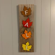 a wooden sign with the word fall spelled out in different colors and shapes on it