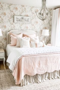 a bedroom with floral wallpaper and pink bedding, chandelier hanging from the ceiling