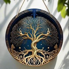 a blue and gold plate with a tree design on the front, hanging from a hook