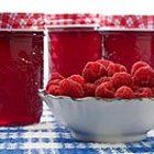 some raspberries are in a bowl on a blue and white checkered tablecloth