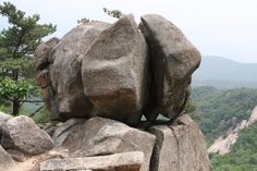 large rocks on top of a mountain with trees in the background