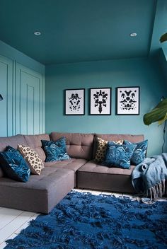 a living room filled with furniture and blue rugs on the floor in front of two framed pictures