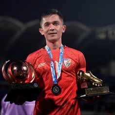 the soccer player is holding two trophies in one hand and an award in the other