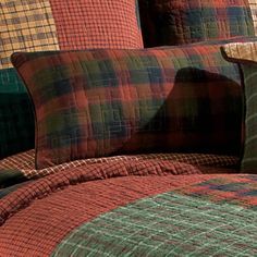 a bed with plaid sheets and pillows on it