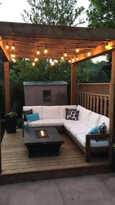 an outdoor living area with couches, tables and lights on the roof above it