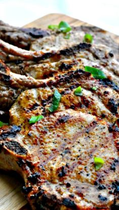 grilled steaks on a cutting board with green garnishes and seasoning