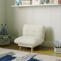 a white chair sitting on top of a hard wood floor next to a book shelf