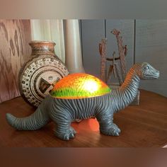 a dinosaur lamp sitting on top of a wooden table