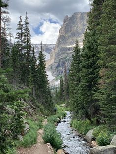 a man is walking down a trail in the mountains