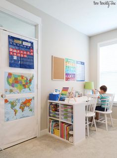 a child sitting at a desk in front of a door with a map on it