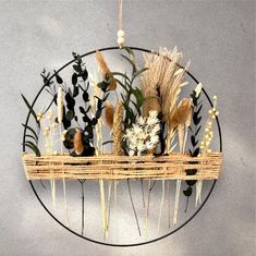 a metal wall hanging with flowers and plants on it's sides in front of a gray wall