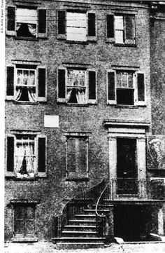 an old black and white photo of a building with windows on the front, stairs leading up to the second floor