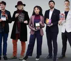 five people standing in front of a white background holding up some kind of electronic devices