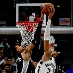 two basketball players are trying to block the ball from going into the basket during a game