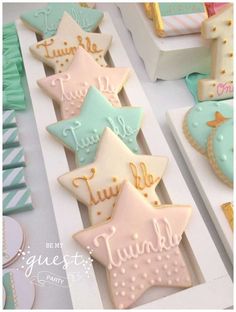 decorated cookies are sitting on white boxes with blue and pink frosting in the shape of stars