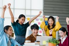 a group of people celebrating in front of a laptop computer