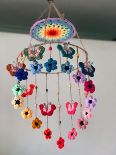 a crocheted mobile with flowers and butterflies hanging from it