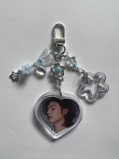 a heart shaped key chain with a photo and charms hanging from it's side