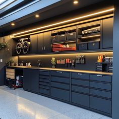 a garage with lots of black cabinets and drawers on the wall, along with two bicycles