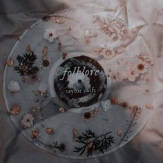 a glass plate with flowers and leaves on it that says folkloree taylor swift in the center