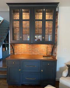 a kitchen with blue cabinets and stairs in the back ground, next to a white couch