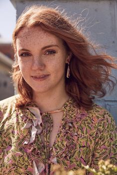 a woman with freckled hair standing in front of a building