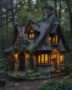 a small stone house in the woods with lights on it's windows and roof